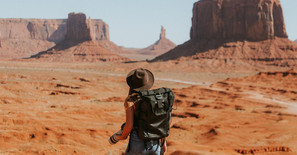 woman standing in a desert with her backpack and camera